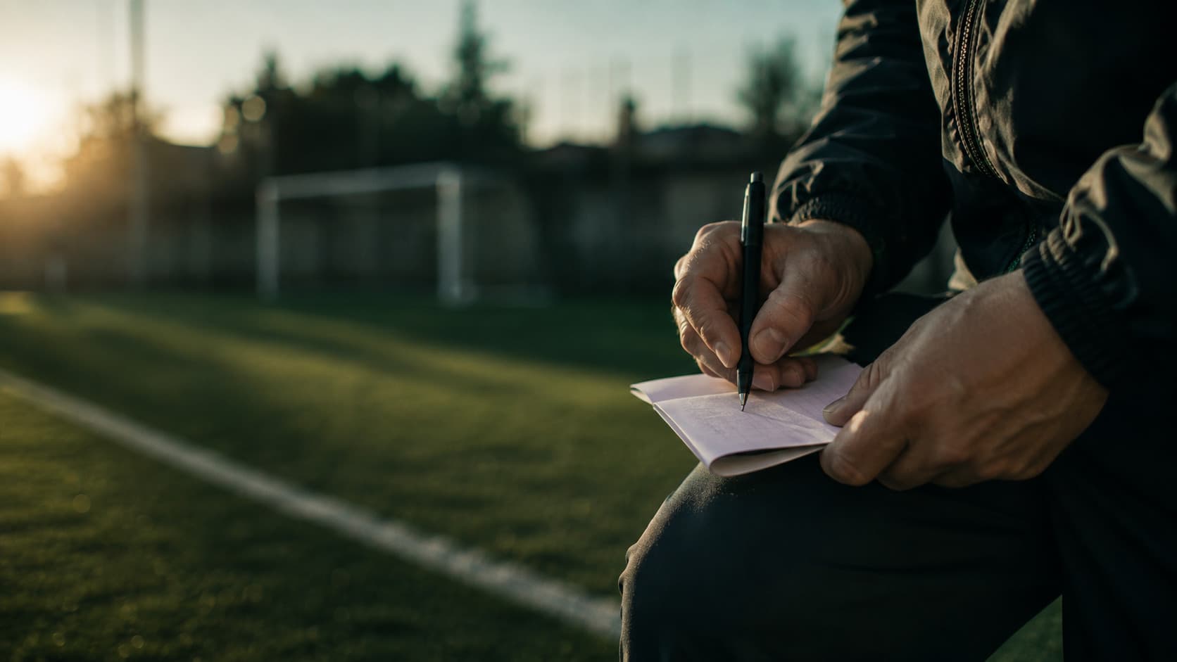 Allenatore in piedi a bordocampo con un foglio in mano negli ultimi minuti di una partita